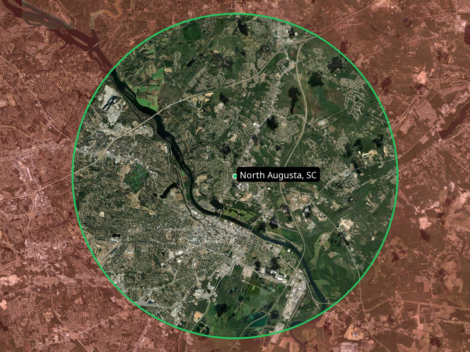 Bird's-eye satellite map of North Augusta, SC inside a green circle — the included service area. Everything outside the circle is shaded red, meaning a mobile fee applies.